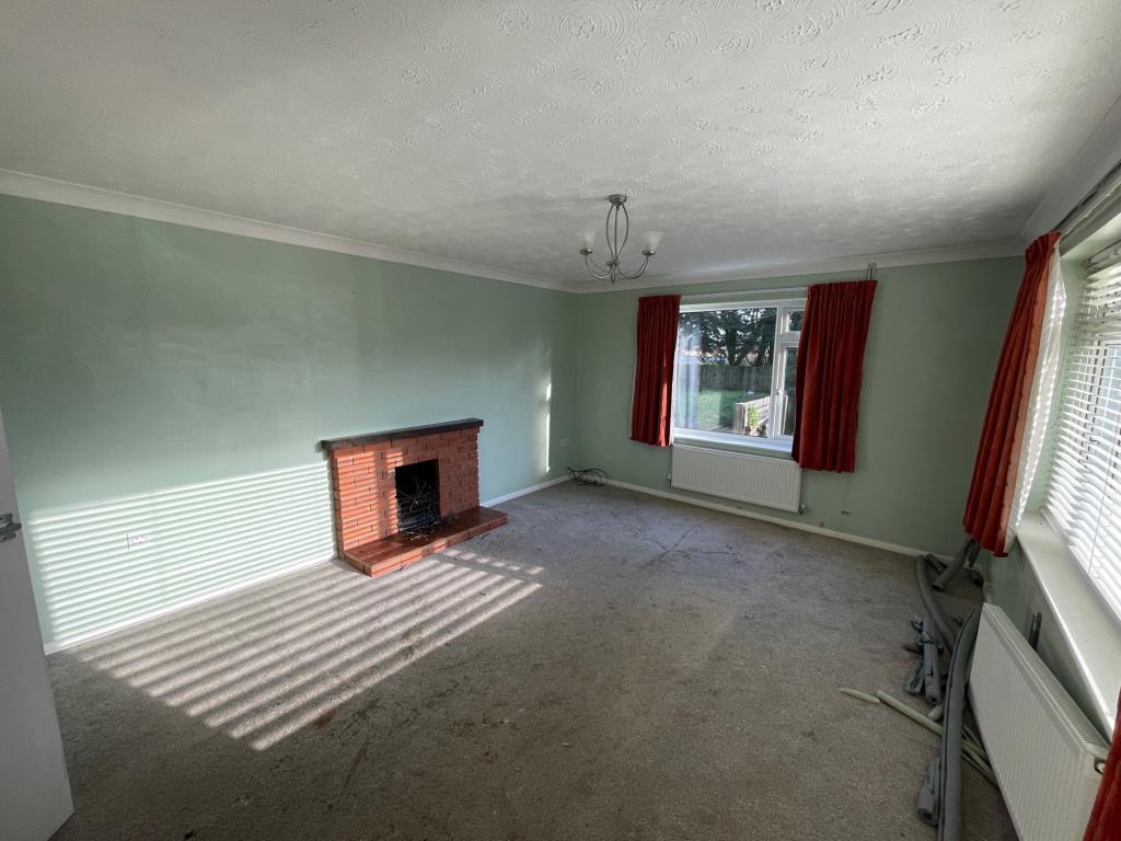 Lot: 76 - A DETACHED BUNGALOW FOR IMPROVEMENT AND REPAIR - Living room with fireplace and dual aspect windows
